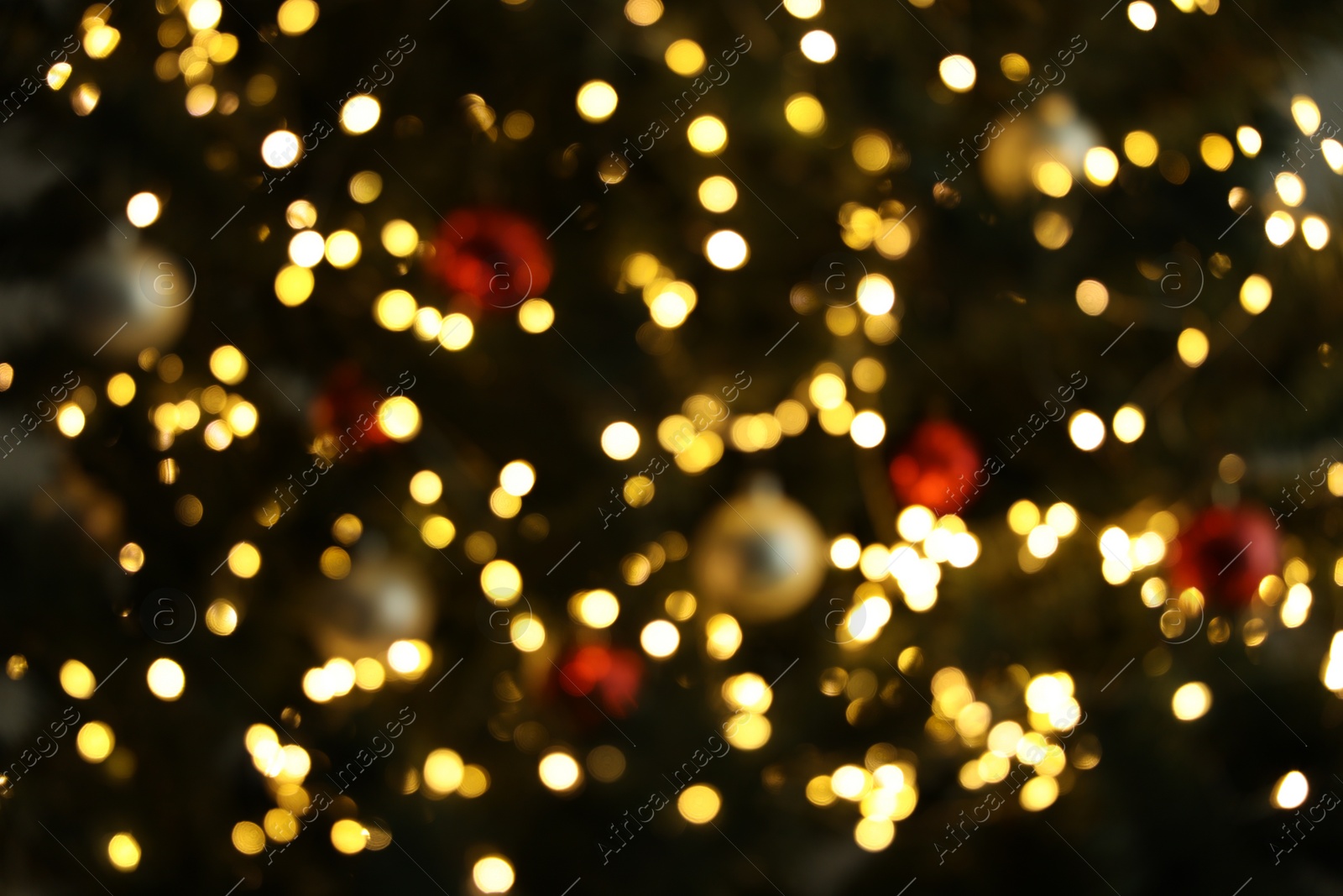 Photo of Blurred view of Christmas tree with bright fairy lights and ornaments, closeup. Bokeh effect