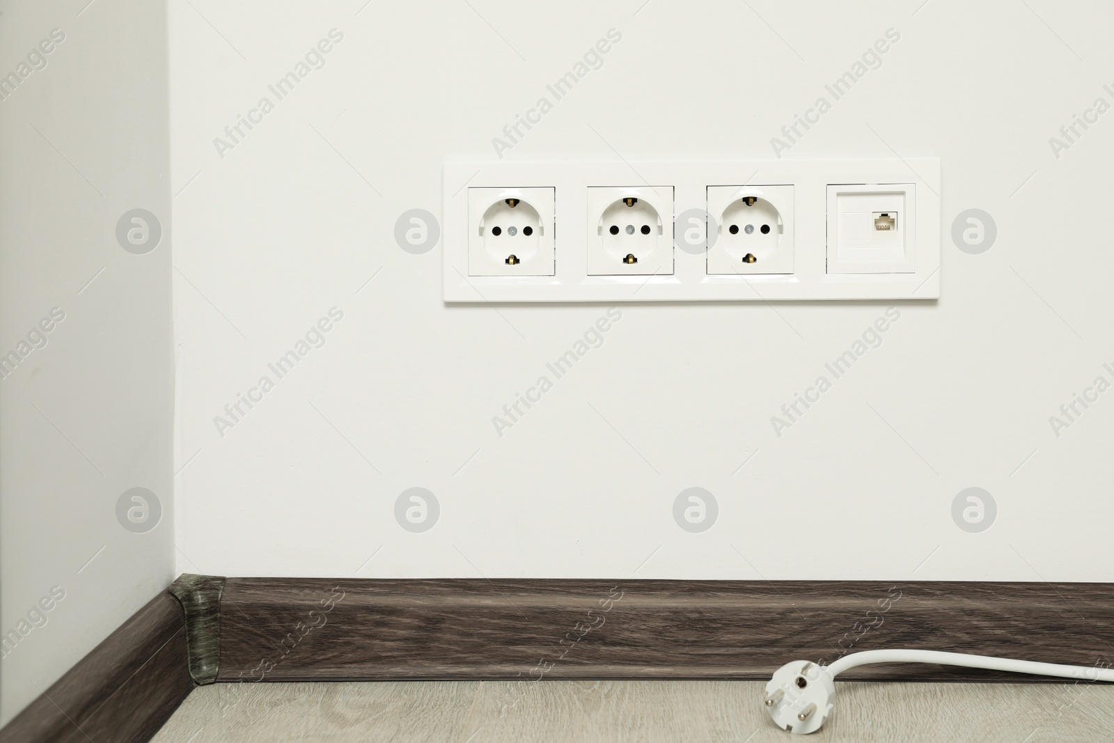 Photo of Plug near white wall with power sockets indoors. Electrical supply
