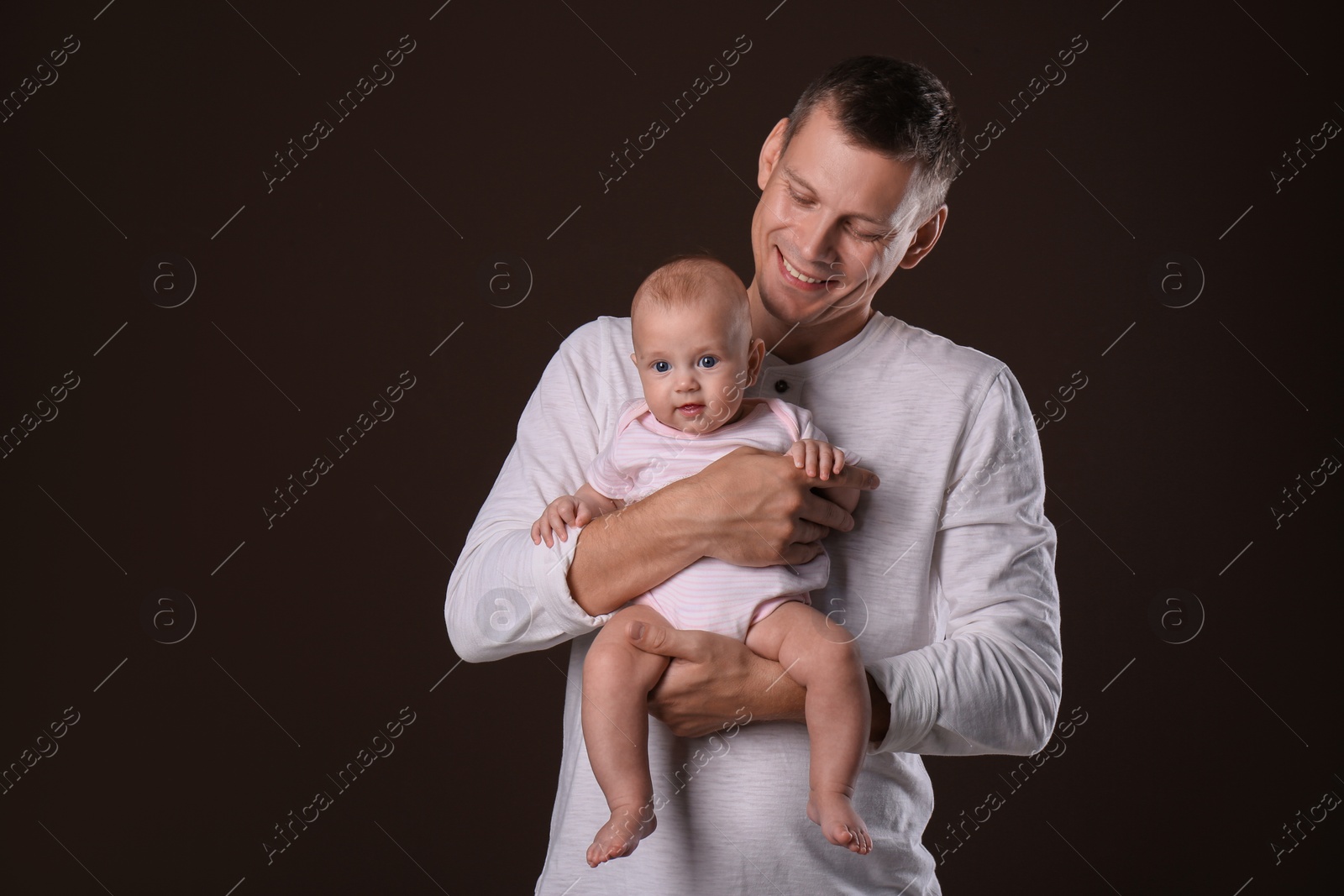 Photo of Happy father with his little baby on dark background