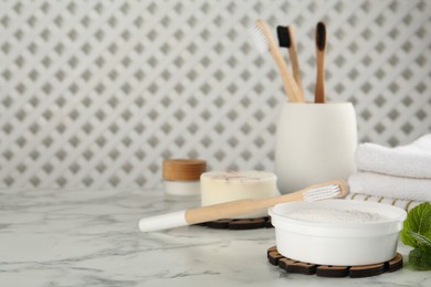 Composition with tooth powder and brushes on white marble table, space for text