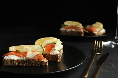 Photo of Delicious bruschettas with salmon served on black table