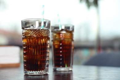 Glasses with refreshing cola and ice cubes on table indoors. Space for text