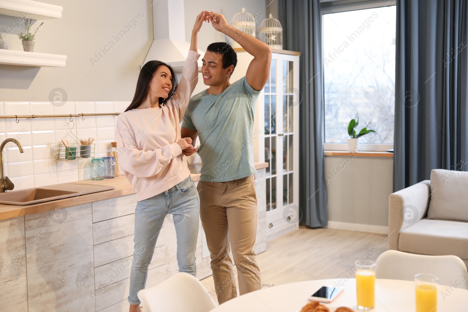 Photo of Lovely young interracial couple dancing at home. Space for text