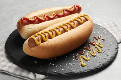 Delicious hot dogs with mustard and ketchup on light grey table, closeup