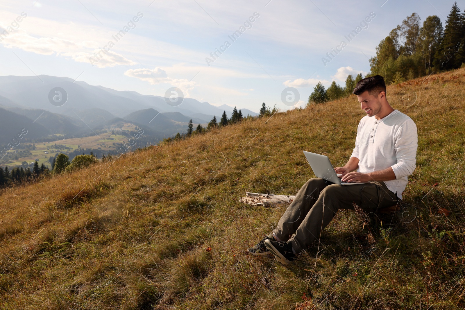 Photo of Man working with laptop outdoors surrounded by beautiful nature. Space for text