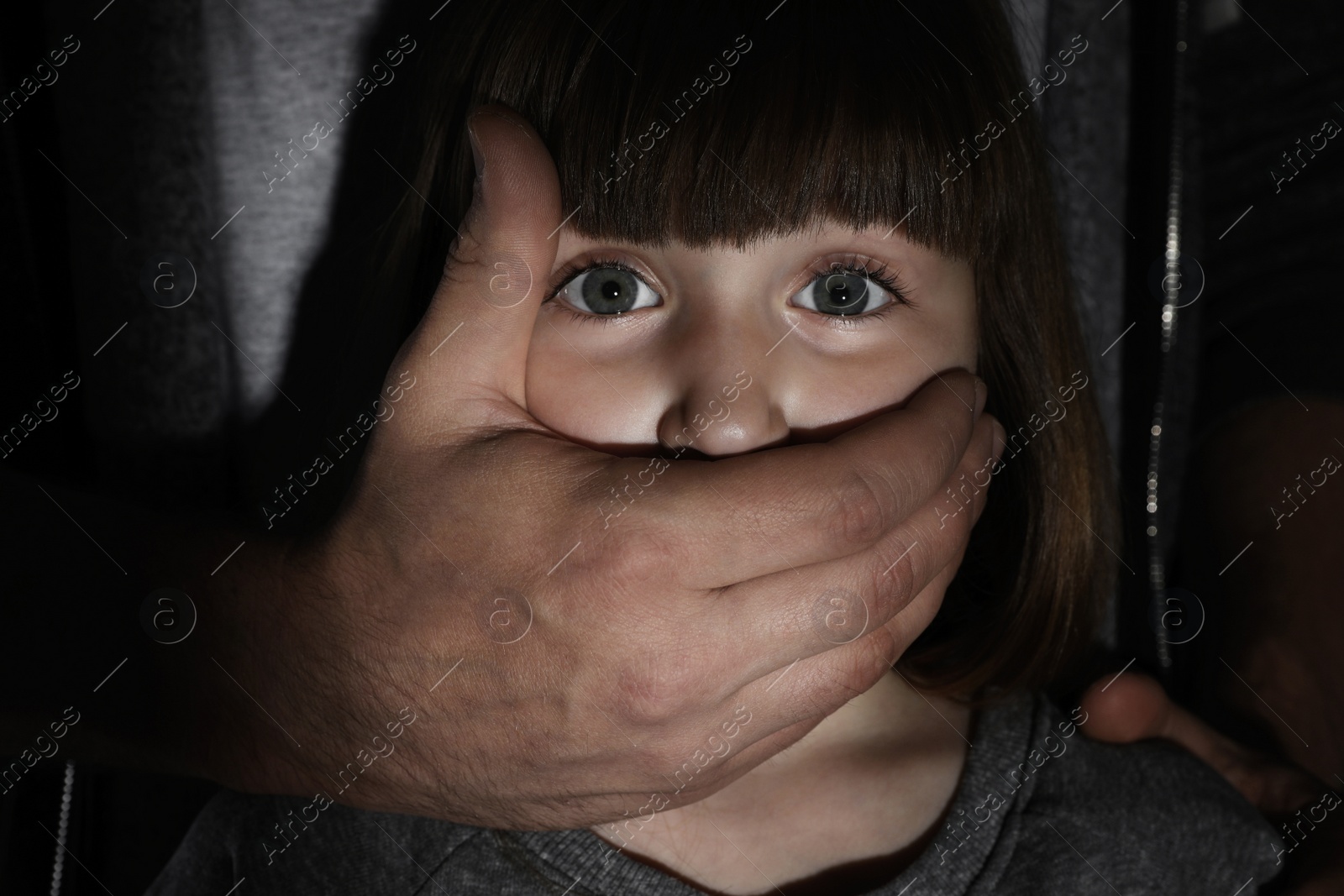 Photo of Adult man covering scared little girl's mouth, closeup. Child in danger