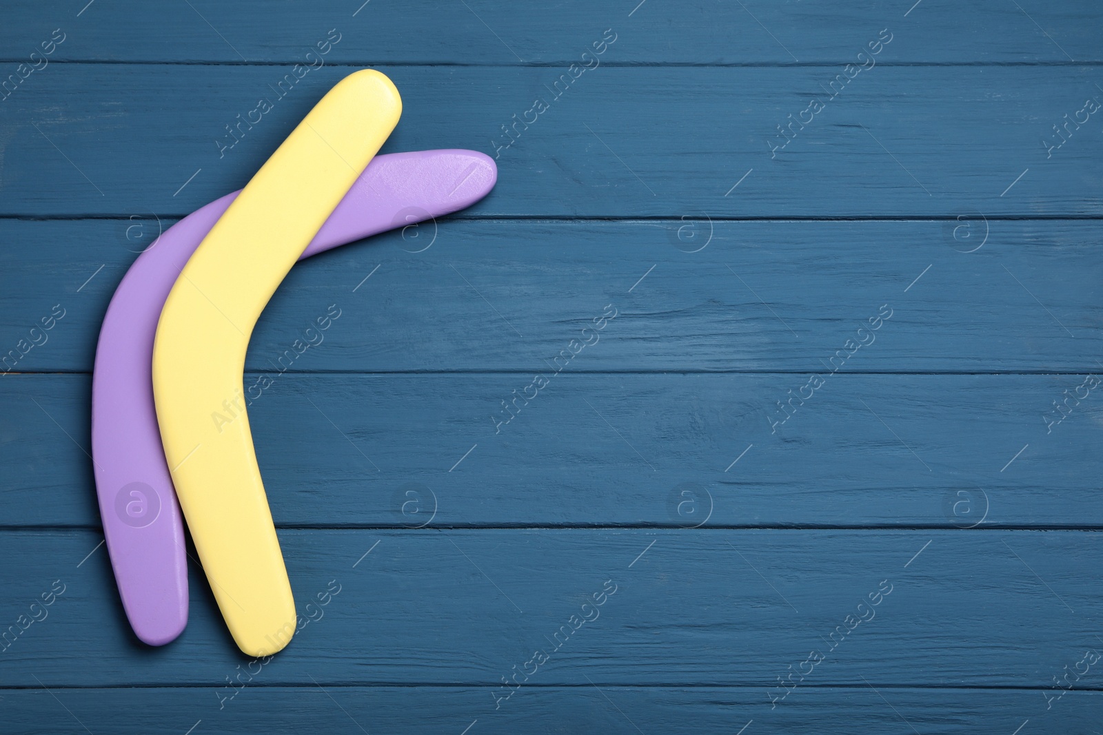 Photo of Boomerangs on blue wooden background, flat lay. Space for text