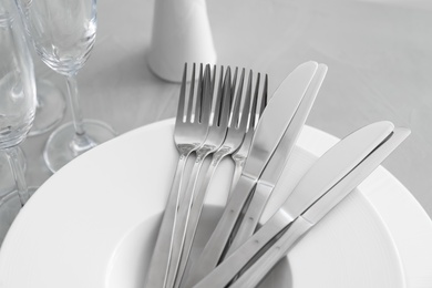 Photo of Plates with knives forks on light grey table, closeup