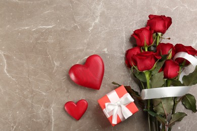 Photo of Flat lay composition with beautiful red roses and gift box on grey background, space for text. Valentine's Day celebration