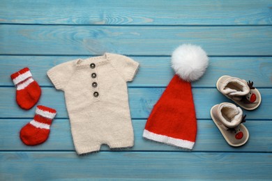 Photo of Set of baby clothes for Christmas photoshoot on light blue wooden background, flat lay