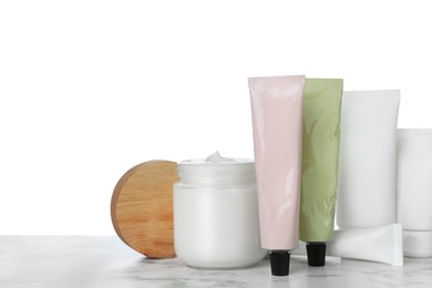 Photo of Set of cosmetic products in jar and tubes on marble table against white background