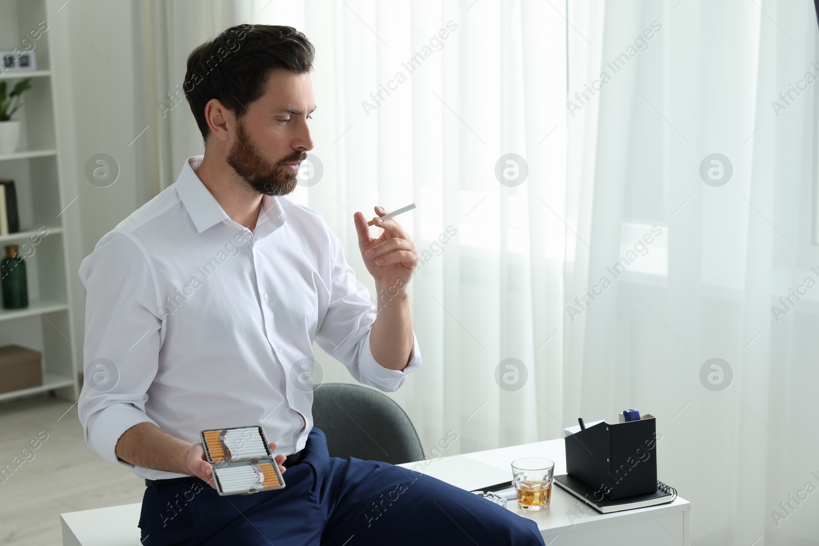 Photo of Man with cigarette and case in office