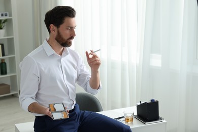 Photo of Man with cigarette and case in office