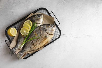 Photo of Seafood. Delicious baked fish served with green onion and lemon on light textured table, top view. Space for text