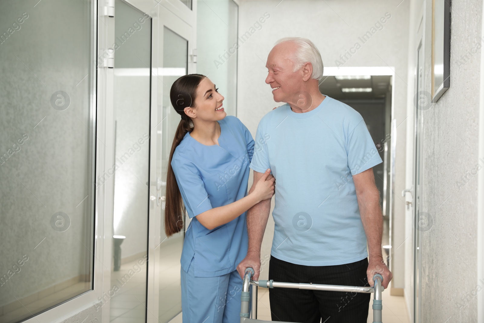 Photo of Nurse assisting senior patient with walker in hospital hallway