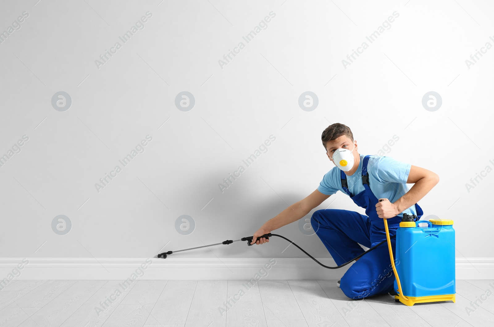 Photo of Pest control worker spraying pesticide in room. Space for text