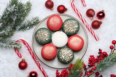 Photo of Beautifully decorated Christmas macarons, candy canes and festive decor on snow, flat lay