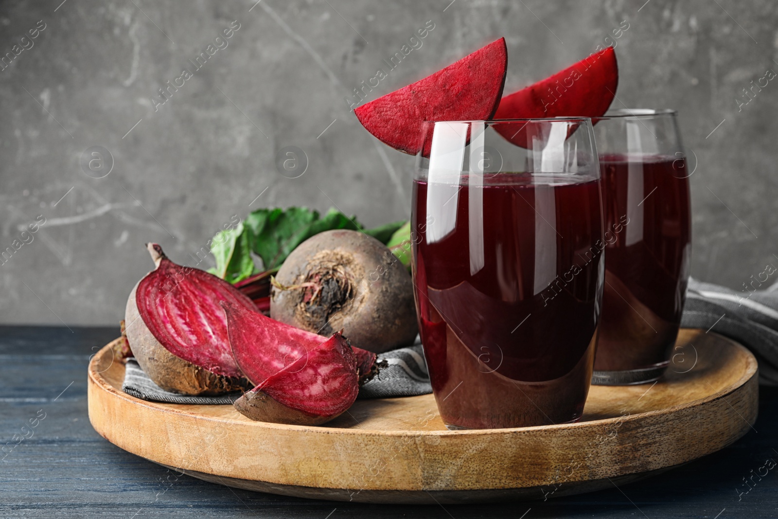 Photo of Tray with beets and glasses of juice on blue wooden table