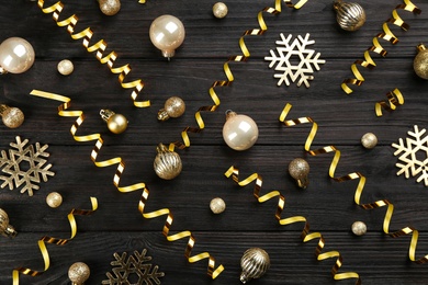 Flat lay composition with serpentine streamers and Christmas decor on black wooden background