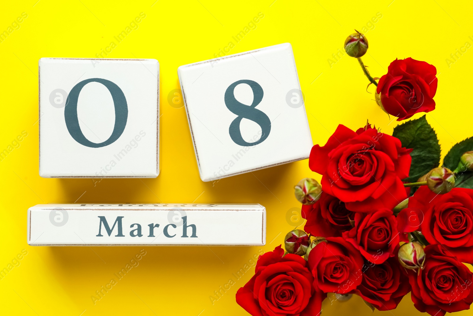 Photo of Wooden block calendar with date 8th of March and roses on yellow background, flat lay. International Women's Day