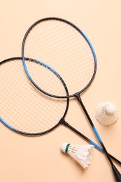 Feather badminton shuttlecocks and rackets on beige background, flat lay