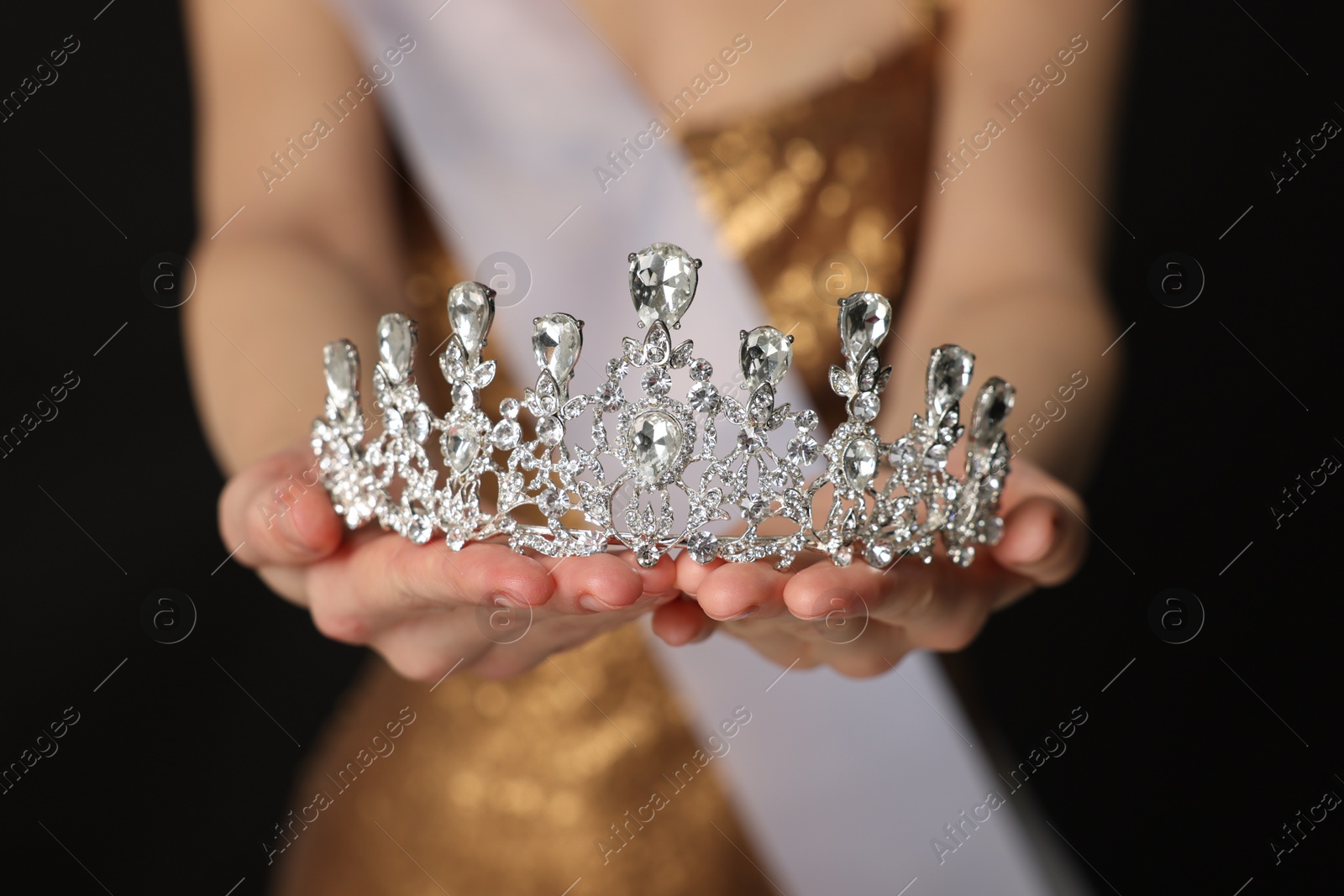 Photo of Woman in dress holding tiara on black background, closeup