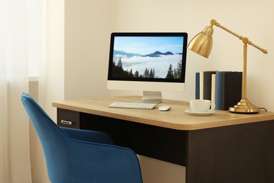 Photo of Cozy workspace with computer on wooden desk and comfortable chair at home