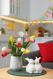 Easter decorations. Bouquet of tulips and bunny figures on table indoors