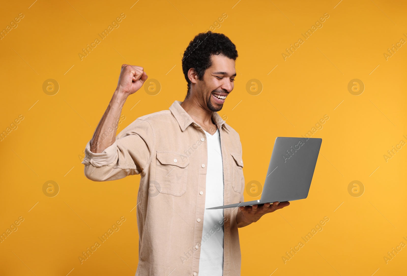 Photo of Emotional man with laptop on orange background