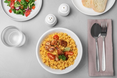 Photo of Delicious rice pilaf served on grey table, flat lay