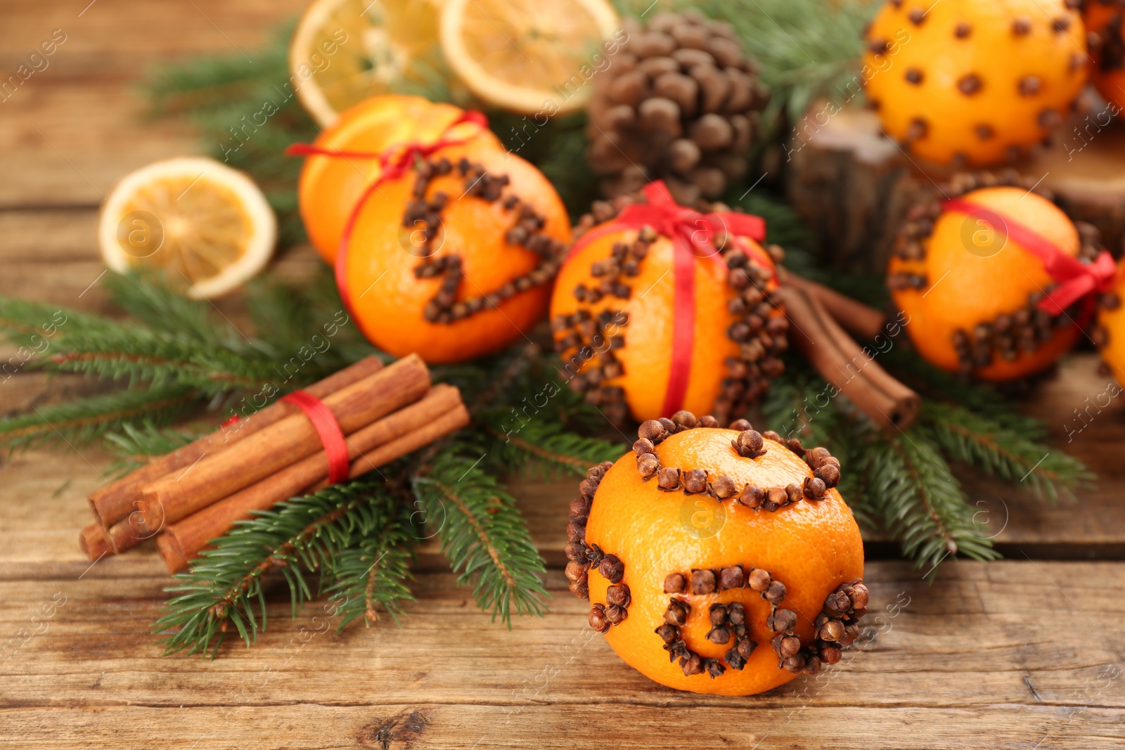 Photo of Pomander ball made of fresh tangerine and cloves on wooden table, space for text