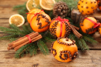 Photo of Pomander ball made of fresh tangerine and cloves on wooden table, space for text