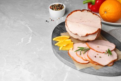 Photo of Delicious sliced ham with orange and rosemary on grey marble table, space for text