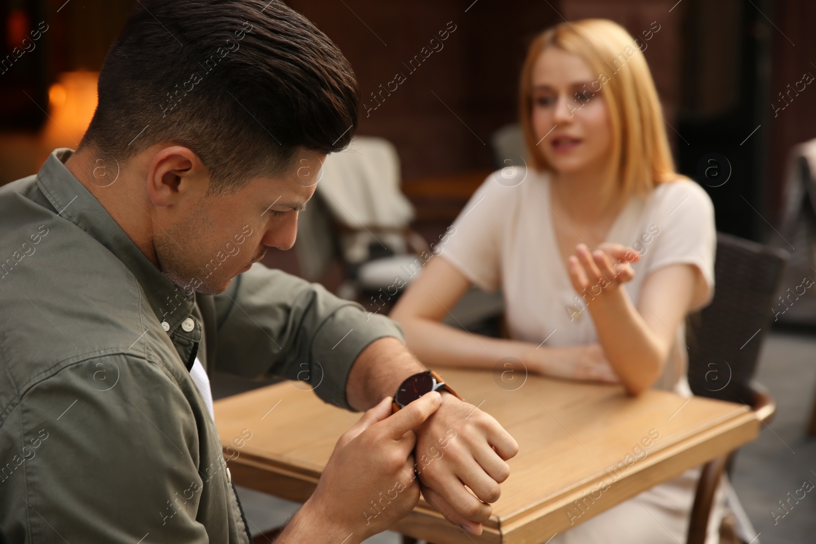 Photo of Man getting bored during first date with overtalkative young woman at outdoor cafe