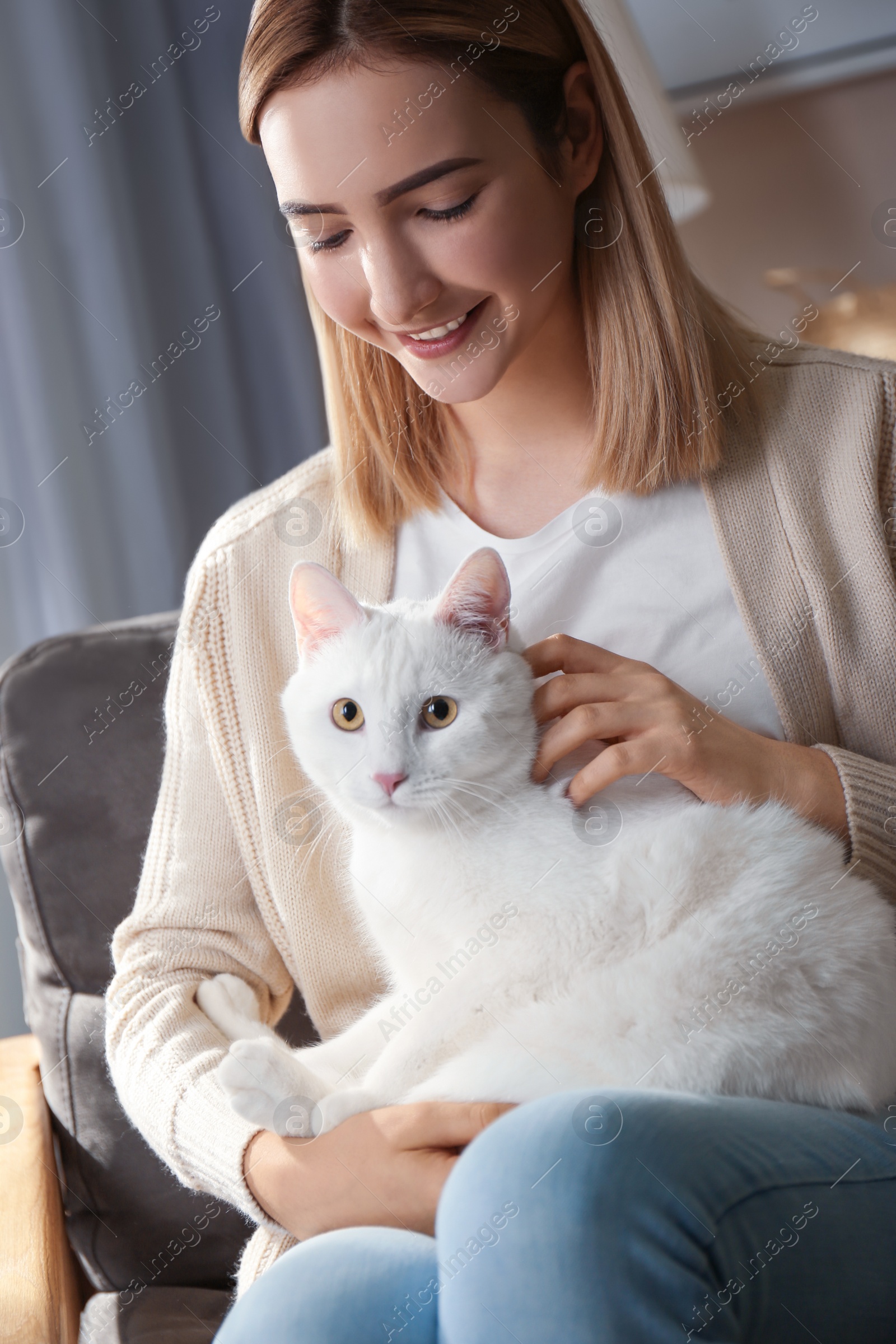 Photo of Young woman with her beautiful white cat at home. Fluffy pet