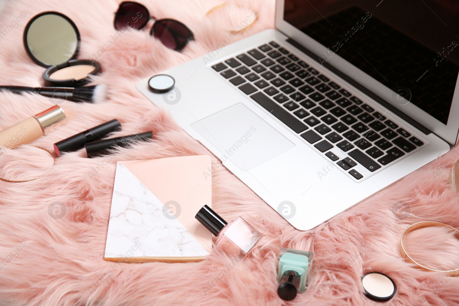 Photo of Composition with laptop, notebook and makeup products for woman on fur