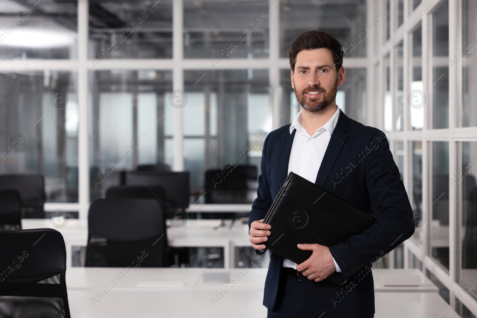 Photo of Happy real estate agent with leather portfolio indoors. Space for text