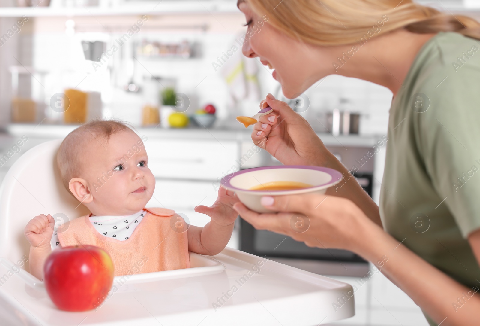 Photo of Woman feeding her child in highchair indoors. Healthy baby food