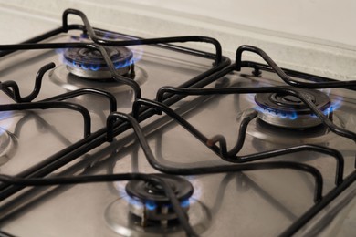 Photo of Gas cooktop with burning blue flames, closeup
