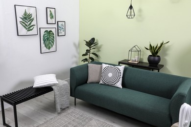 Photo of Stylish living room interior with comfortable green sofa and floral pictures