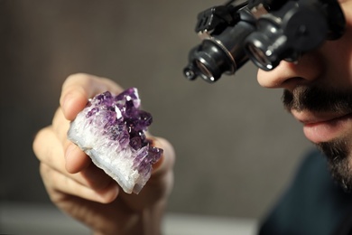 Male jeweler evaluating semi precious gemstone in workshop, closeup