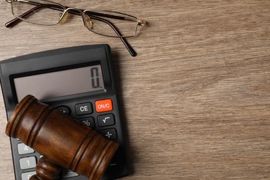 Law. Gavel, calculator and glasses on wooden table, top view. Space for text