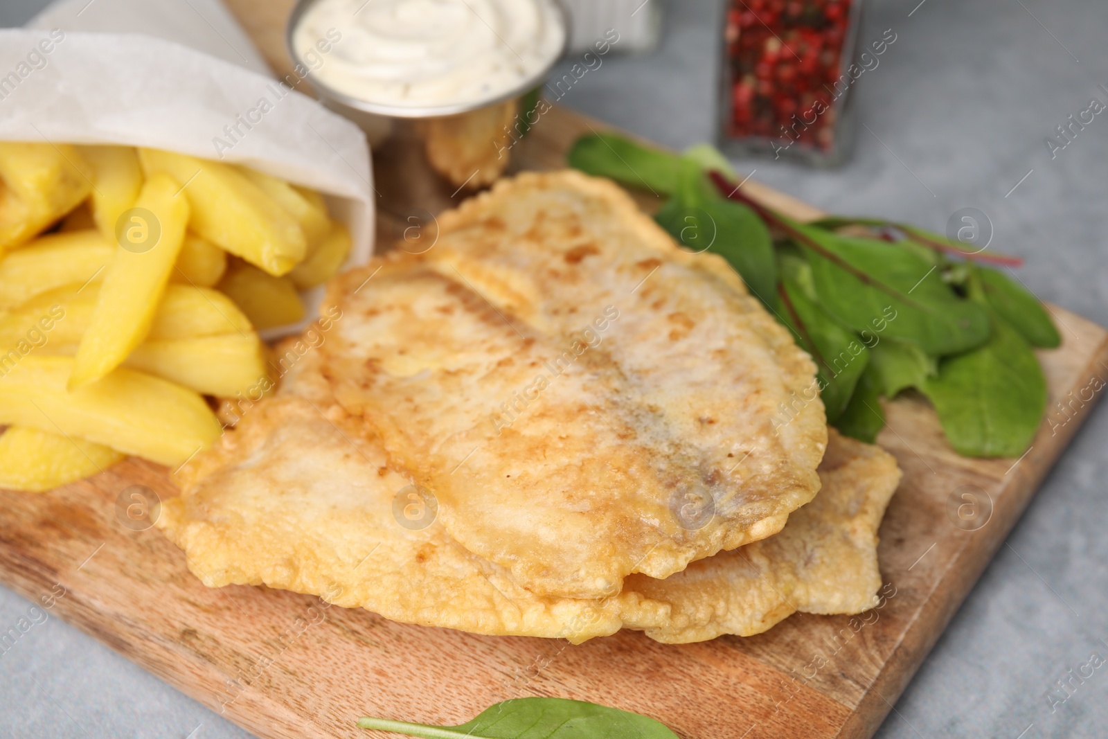 Photo of Delicious fish and chips with mangold on gray table, closeup