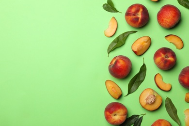 Flat lay composition with sweet juicy peaches on green background, space for text