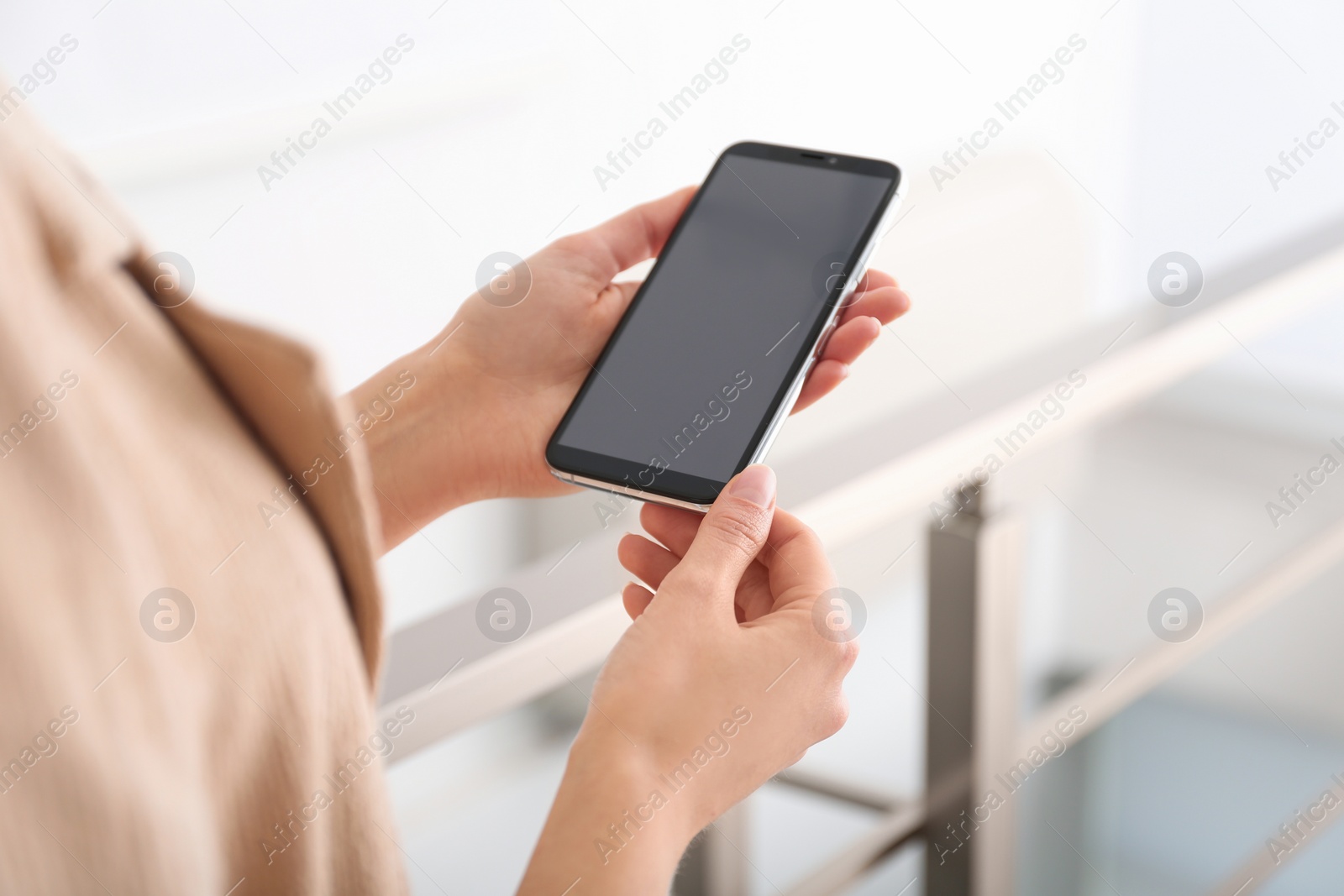 Photo of Young woman using modern smartphone indoors, closeup