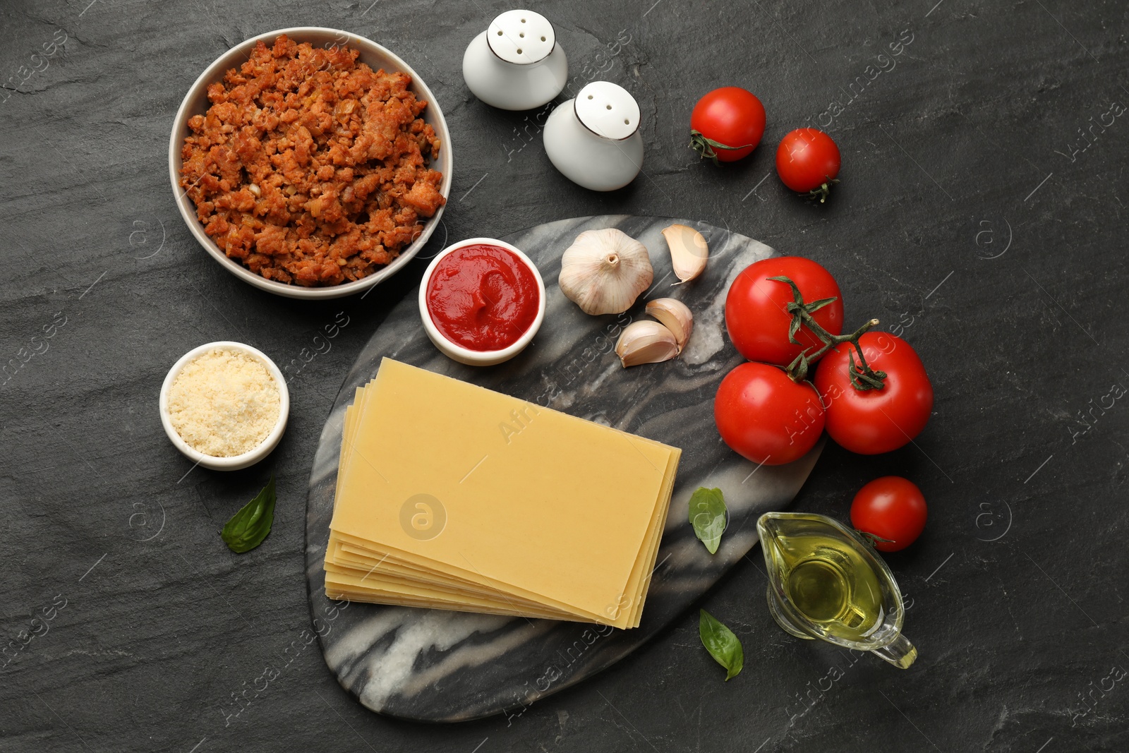 Photo of Flat lay composition with products for cooking lasagna on dark textured table