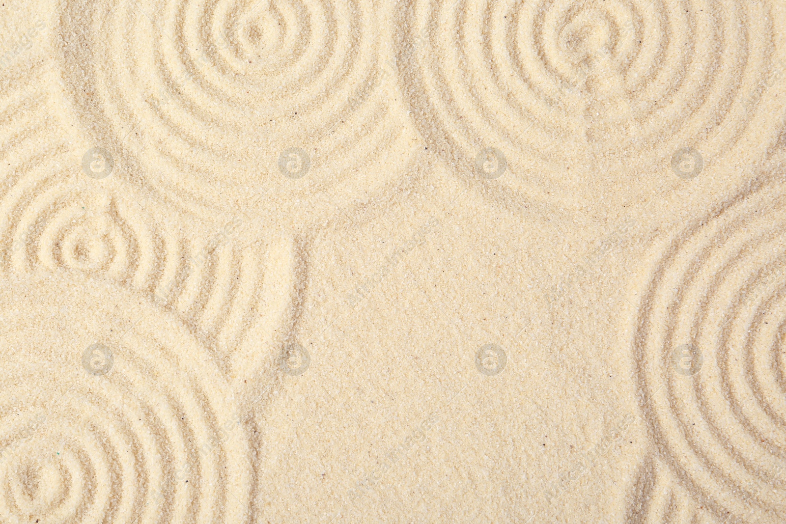 Photo of Zen rock garden. Circle patterns on beige sand, top view