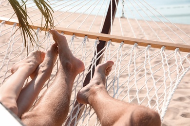 Photo of Young couple relaxing in hammock on beach, closeup