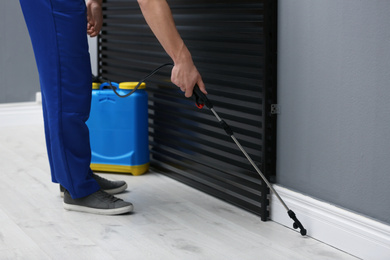 Pest control worker spraying pesticide in room