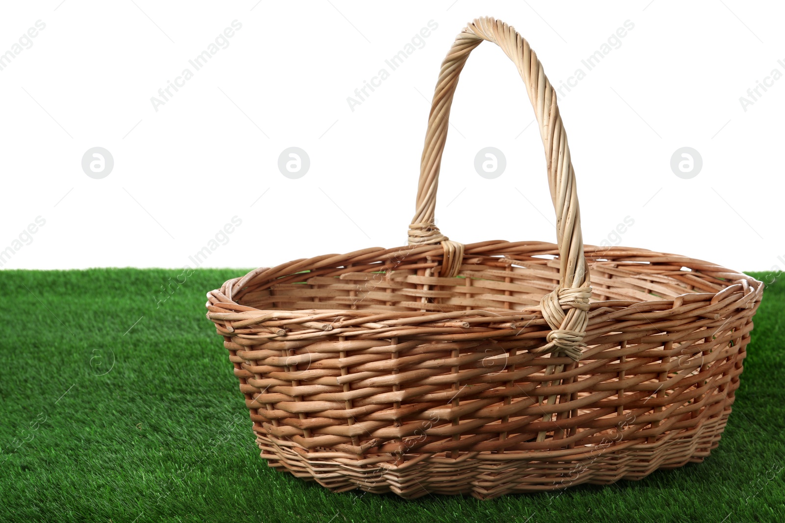 Photo of Empty wicker basket on green lawn against white background. Space for design. Easter item